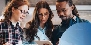 three people looking into tablet talking