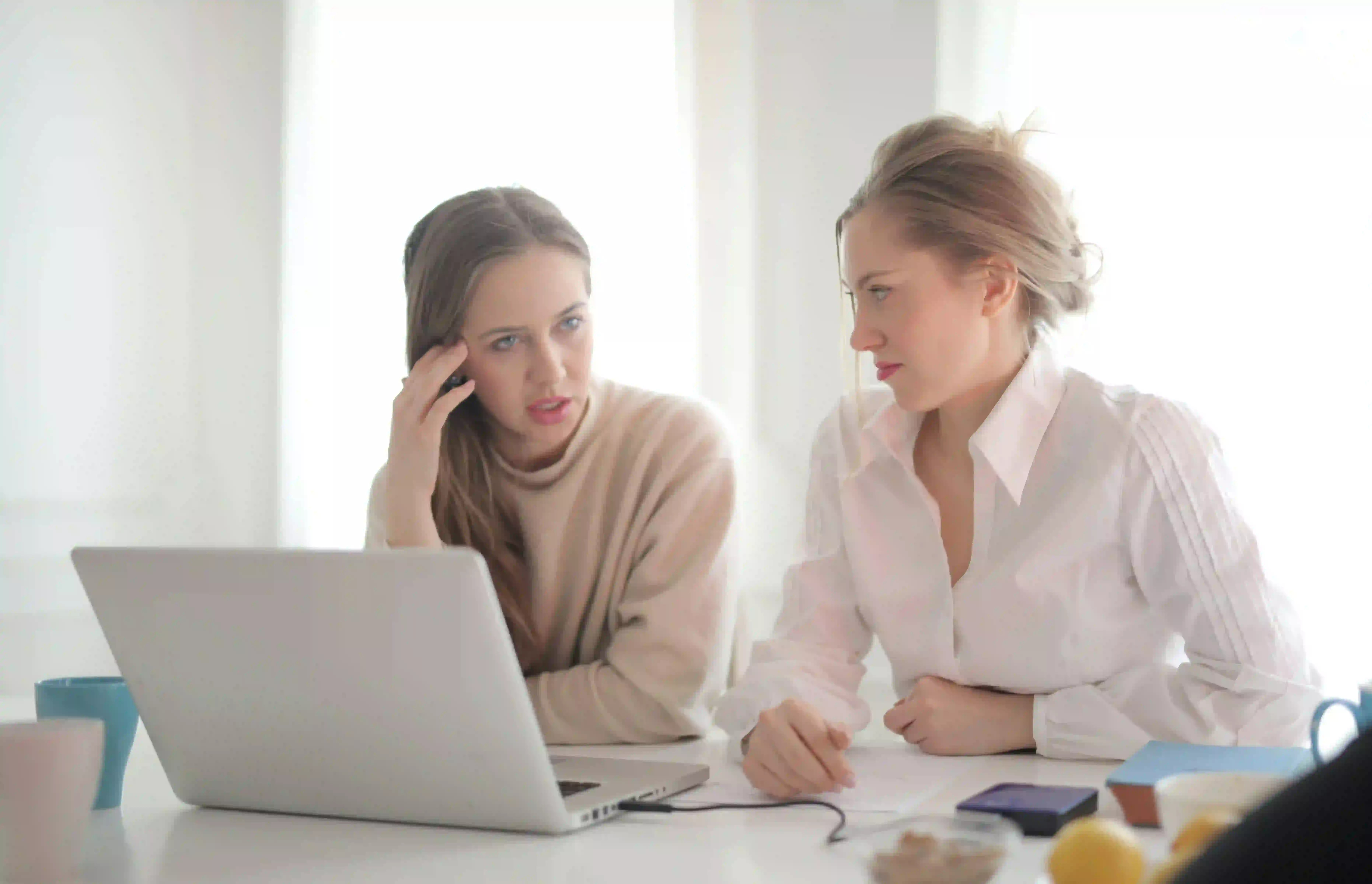 behavioral intelligence versus emotional intelligence with two women sitting at office desk discussing together 